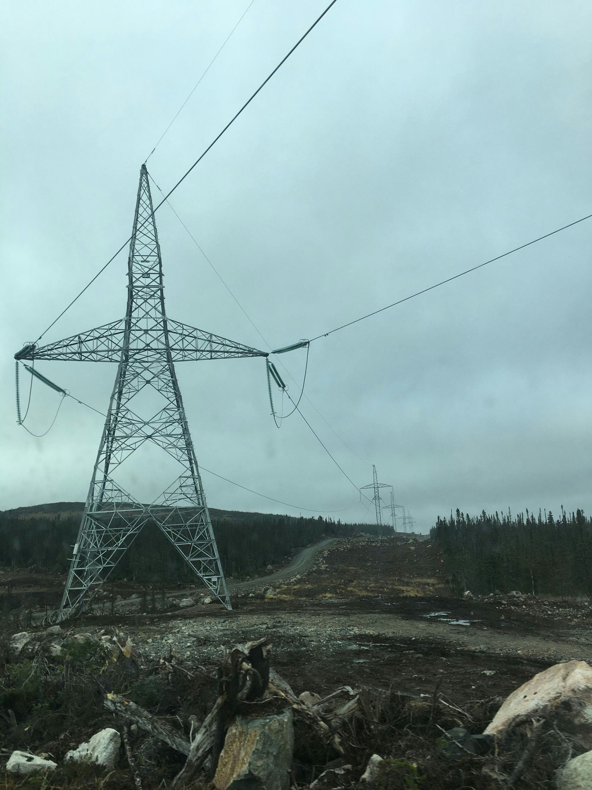 Line of star shaped transmission towers under grey sky