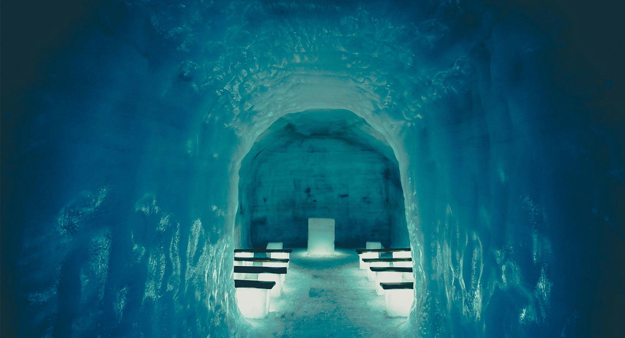 Inside of a blue Ice cave with few illuminating benches 