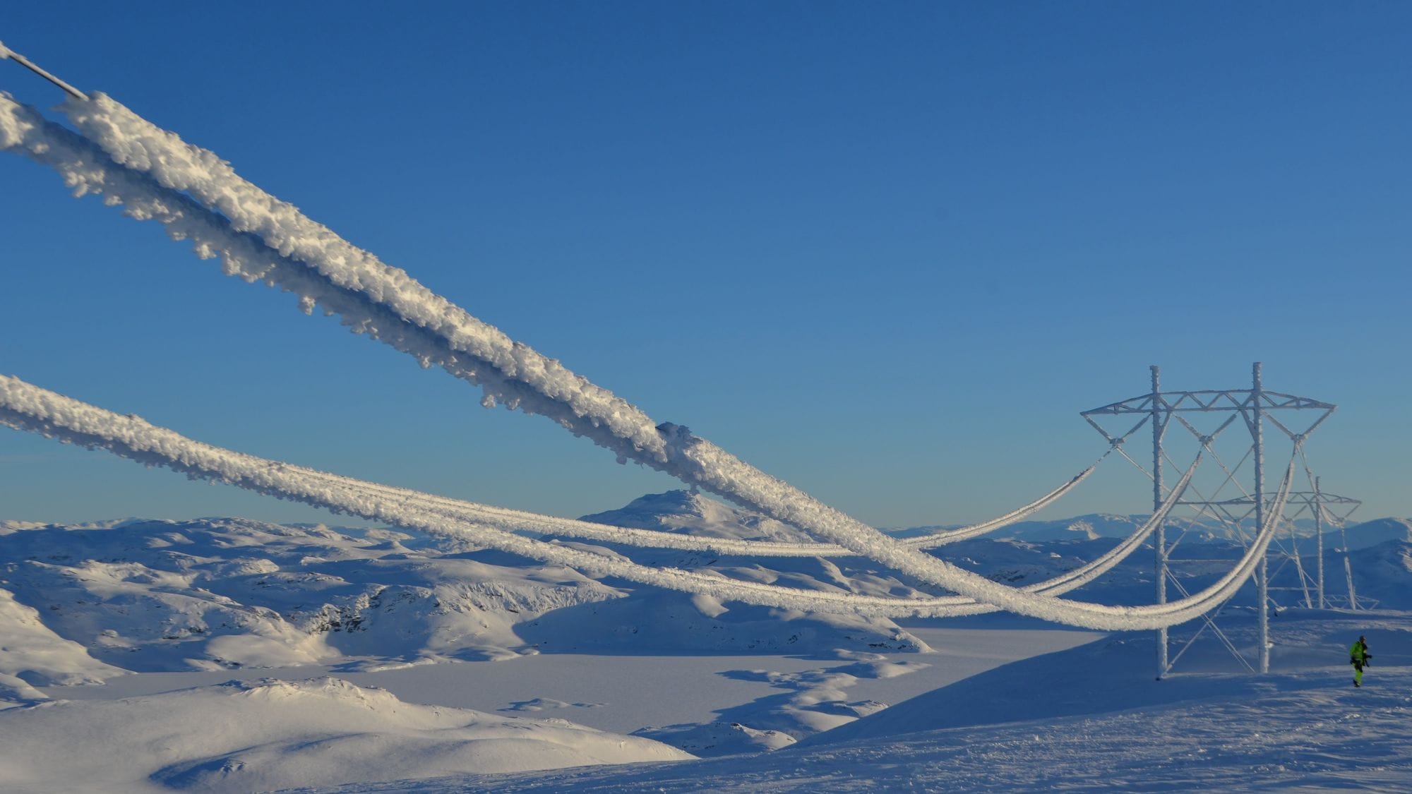 Mast in snow thanks to surroundings with icy electrical wires